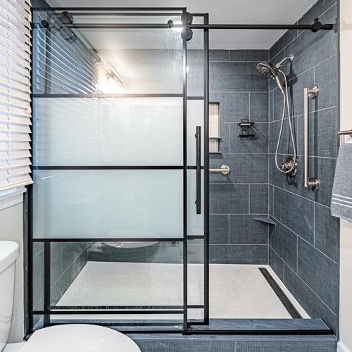 Barn door style shower partition with metal framed clear and frosted glass door